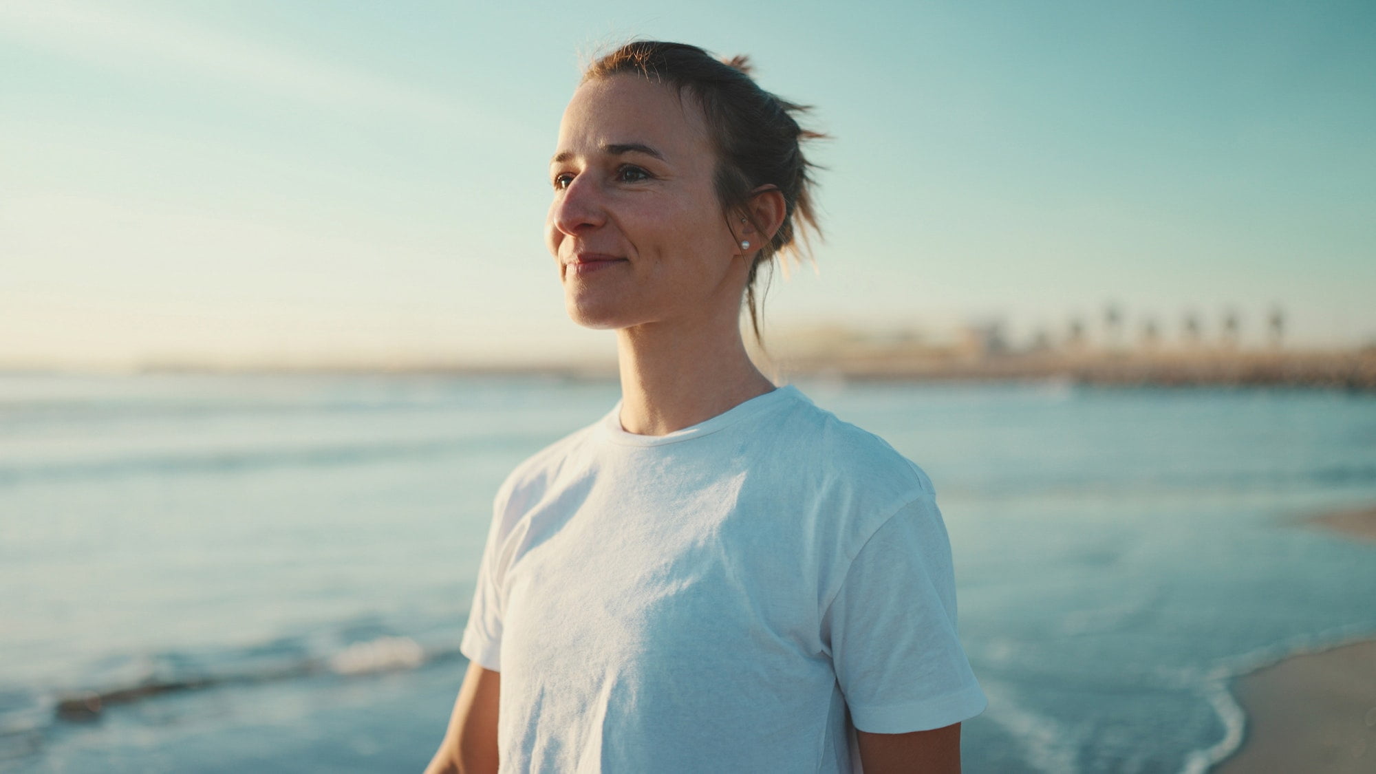 attractive blond woman looking happy walking along the sea after yoga practice 1